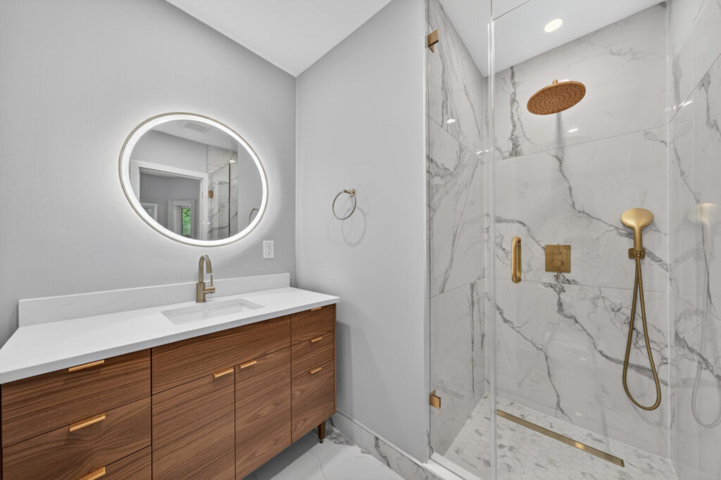 whole home renovation Toronto - Summerhill bathroom with marble-look tile, walk-in glass shower and brass fixtures