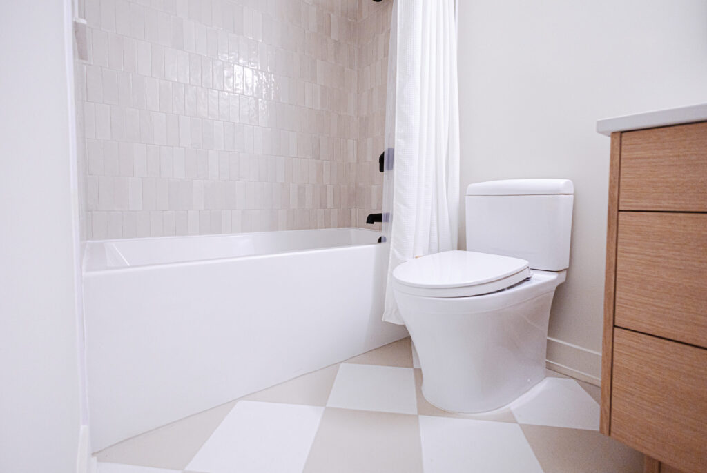 Oak vanity with matte black faucet beside a tiled tub and shower