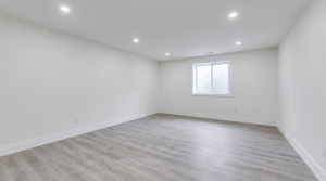 Newly finished empty basement suite with vinyl flooring and an egress window