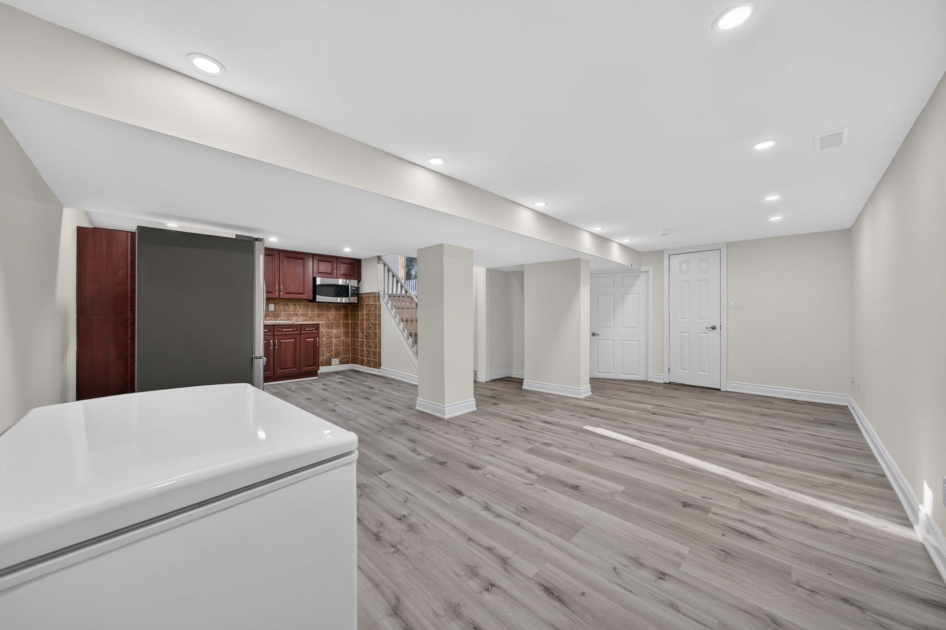 Open basement rec room with boxed structural columns and recessed lighting