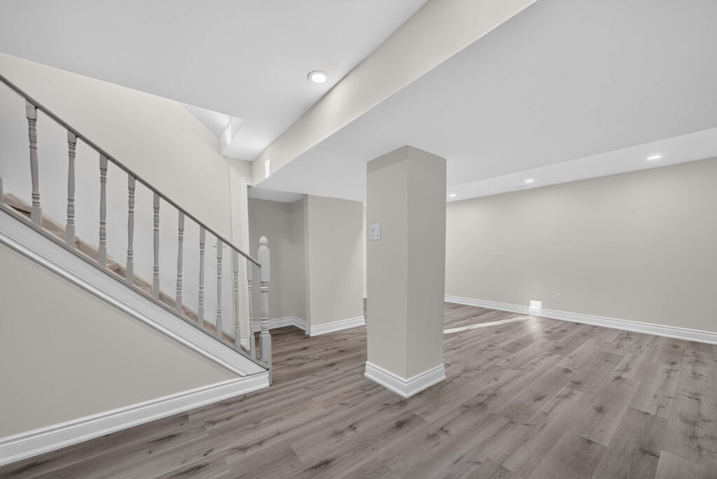 Basement stairs with a white-painted railing beside the finished rec room