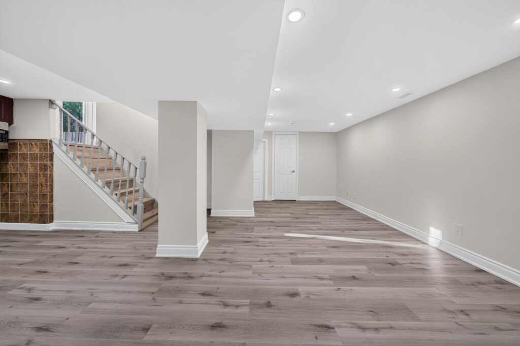 Finished basement with an open layout, flat ceiling and recessed pot lights