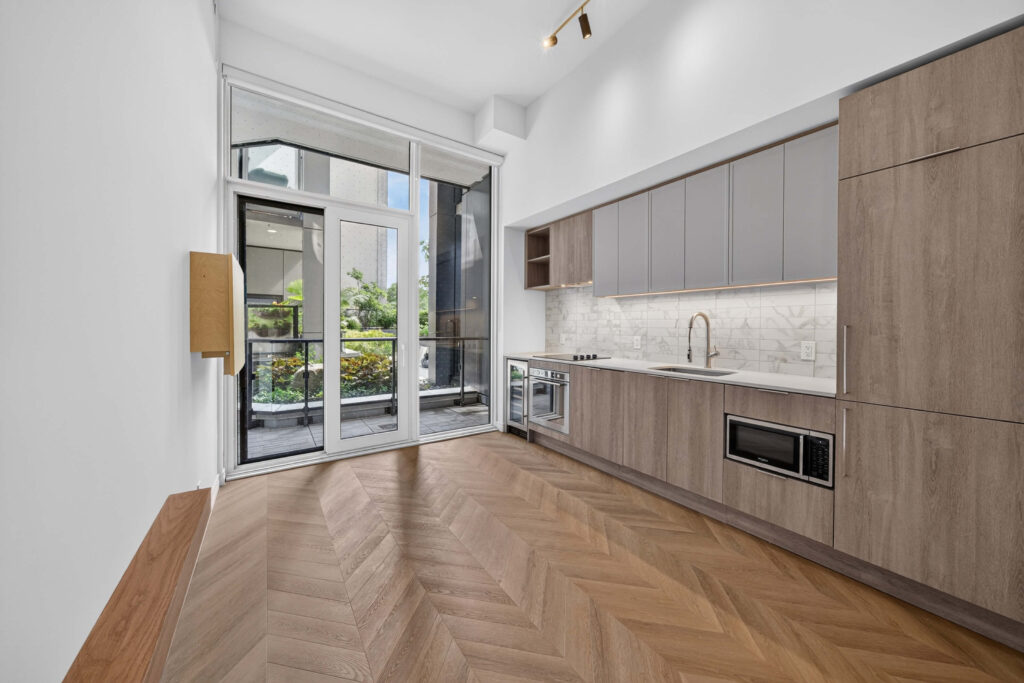 Condo renovation in Toronto with chevron floors and a one-wall kitchen opening to a terrace